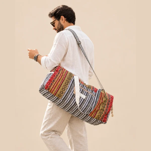 a man carrying colorful and vibrant duffle bag and looking at his phone
