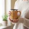 a person holding bamboo coffee mug with handle