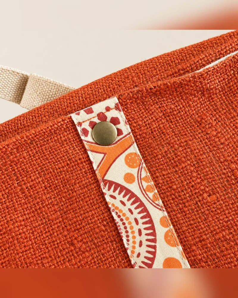 Close-up of rust orange hemp side bag featuring textured natural hemp fabric and colourful patterned snap fastening.