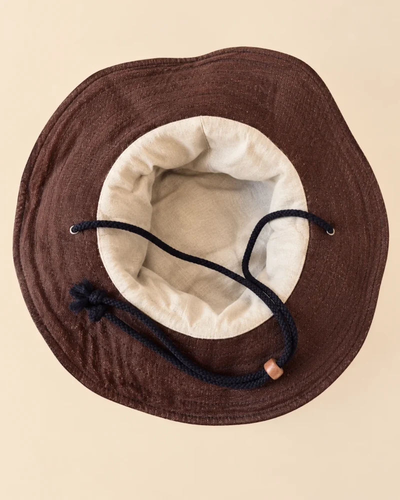 Brown KTM Safari Hat with Chin String handmade from Himalayan hemp, featuring a shapable wide brim, textured crown and black chin cord with wooden adjuster.