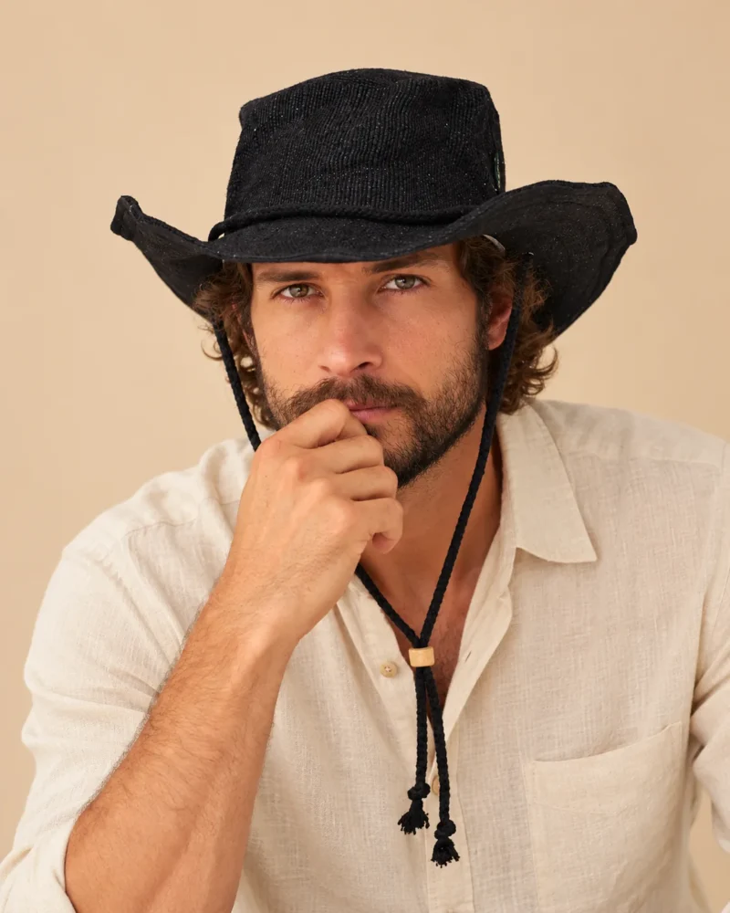 Male model wearing Black KTM Safari Hat with Chin String, featuring a wide shapable brim, woven Himalayan hemp texture and adjustable black chin cord.