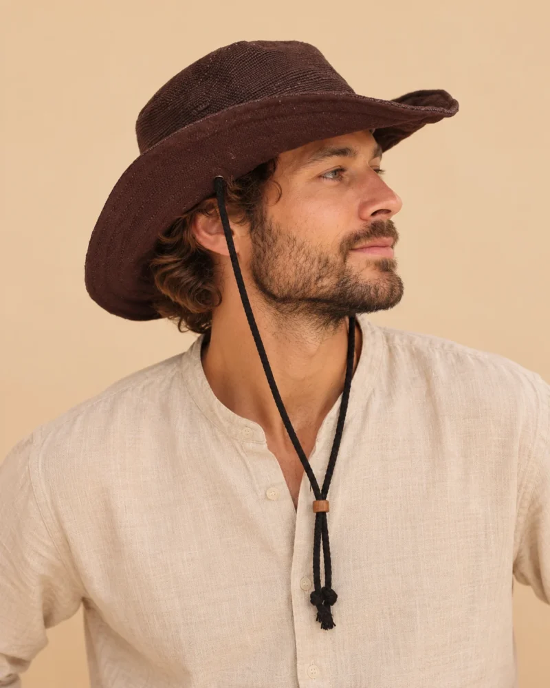 Side profile of male model wearing Brown KTM Safari Hat with Chin String, showing the curved wide brim, woven hemp texture and adjustable chin strap.