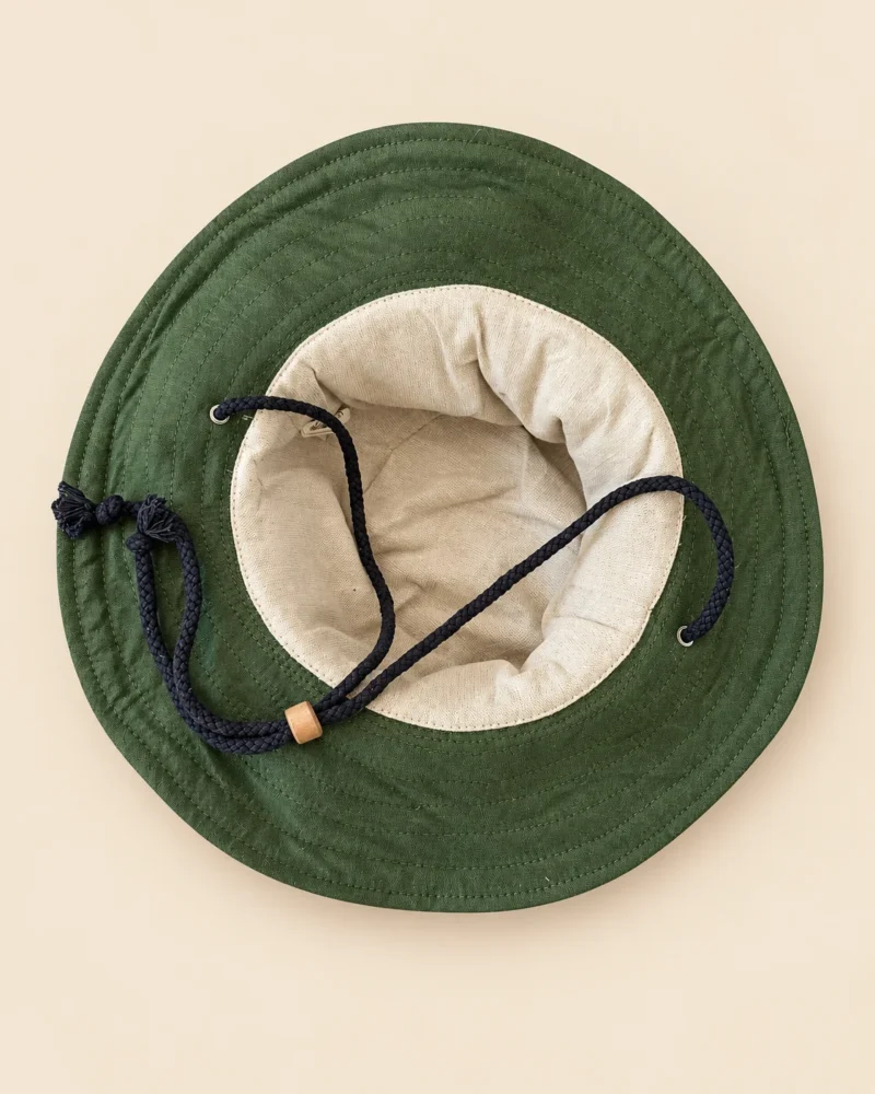 Inside view of Green KTM Safari Hat with Chin String showing soft cotton lining, green wide brim, detailed stitching and adjustable black chin cord with wooden toggle.