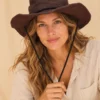 Female model wearing Brown KTM Safari Hat with Chin String, styled with a natural hemp shirt against a plain beige studio background
