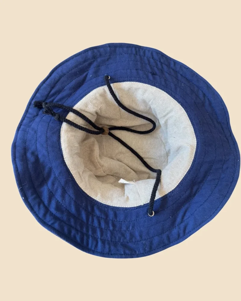 Inside view of Navy Blue KTM Safari Hat with Chin String, showing soft cotton lining, navy blue stitched brim and black chin cord with wooden adjuster.