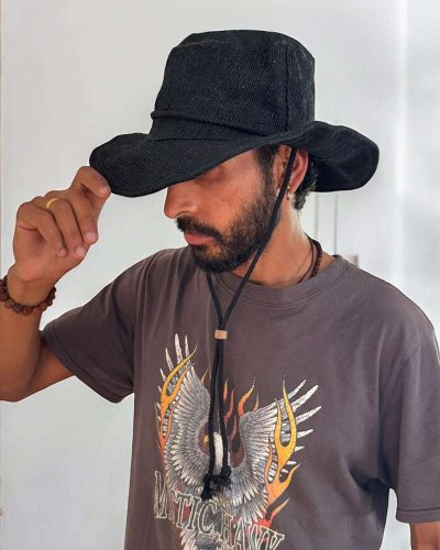 a boy wearing black safari hat with string