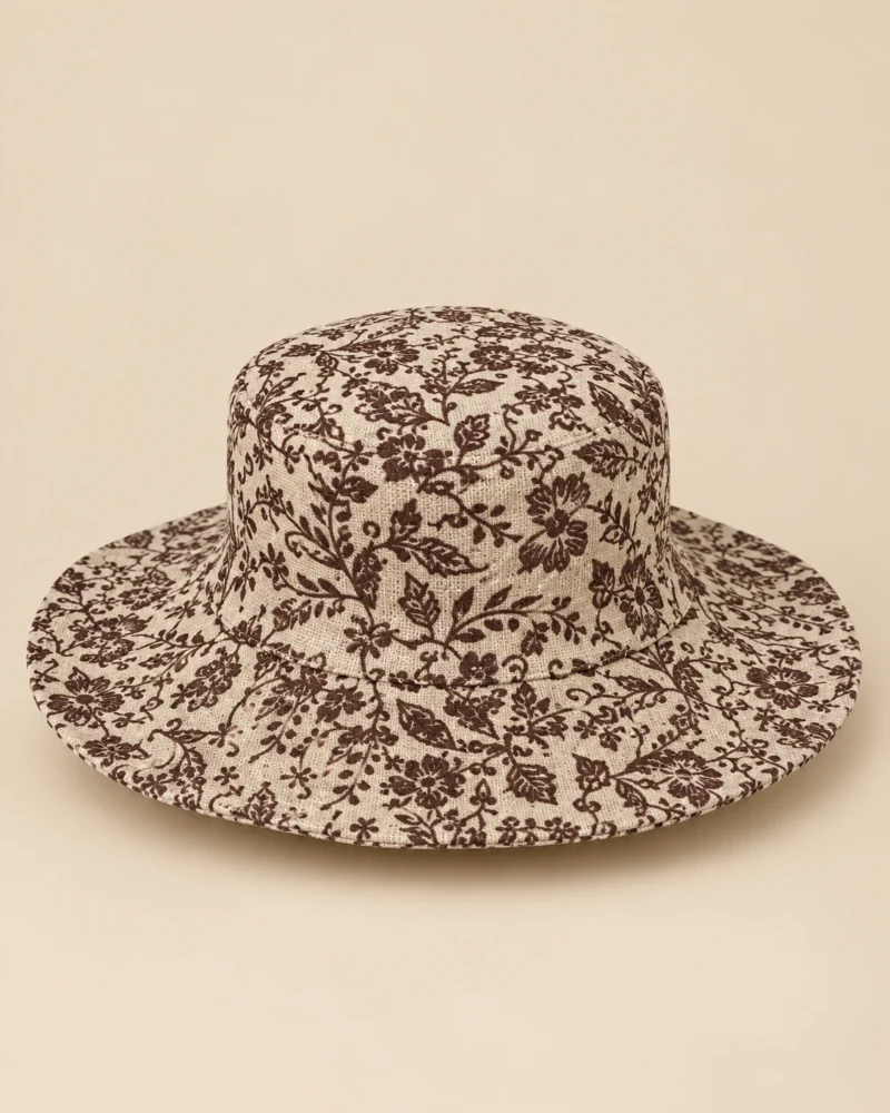 Handmade beige Himalayan hemp hat with dark brown floral print and wide brim, displayed on a plain beige backgroun