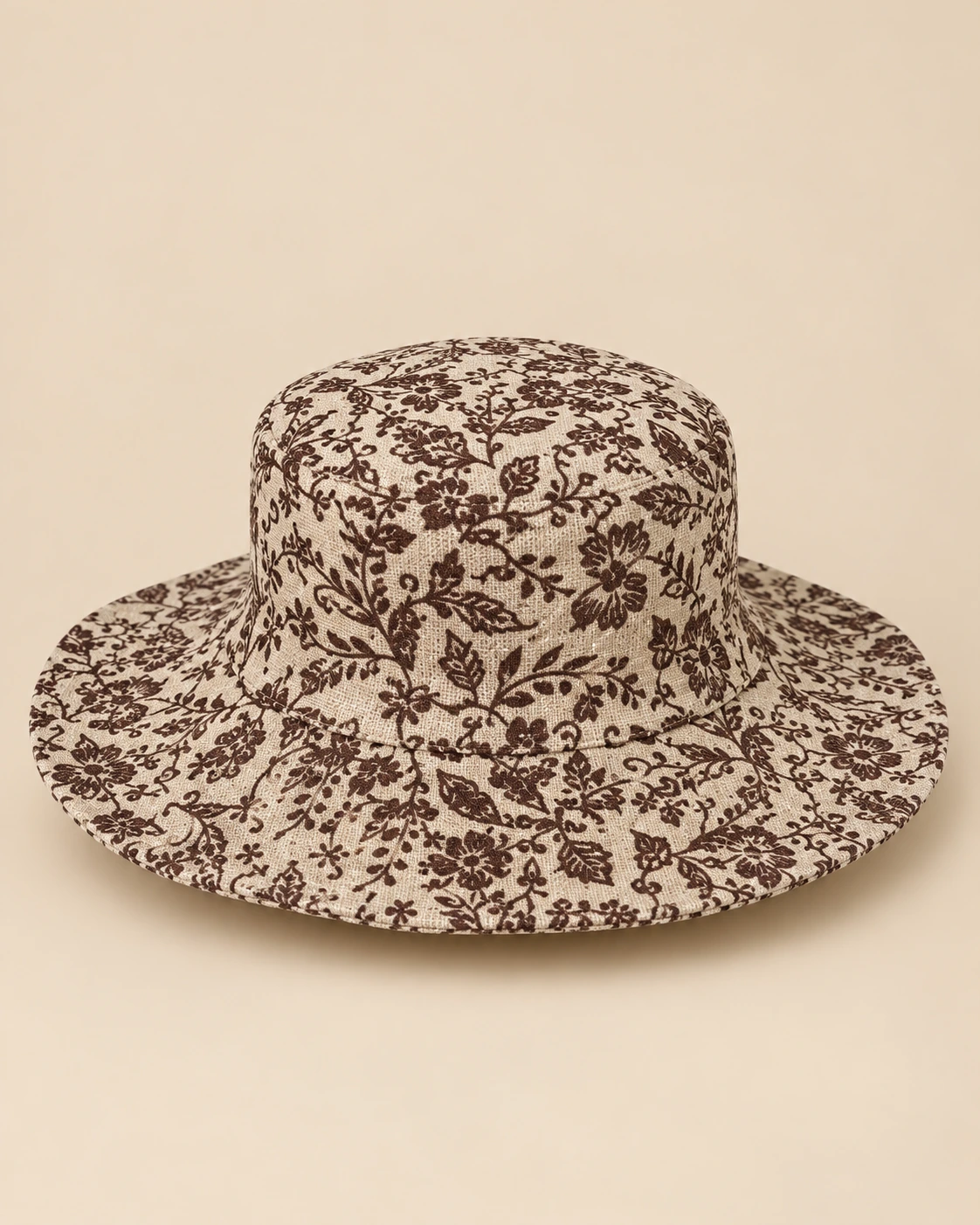Handmade beige Himalayan hemp hat with dark brown floral print and wide brim, displayed on a plain beige backgroun