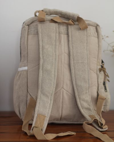Backside of Handmade hemp maternity backpack displayed on a wooden table indoors