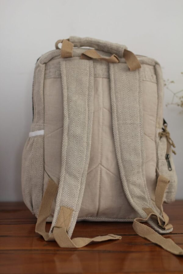 Backside of Handmade hemp maternity backpack displayed on a wooden table indoors