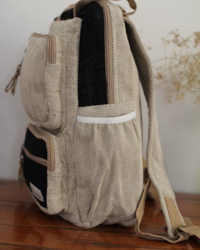 Handmade hemp maternity backpack displayed on a wooden table indoors water bottle compartment