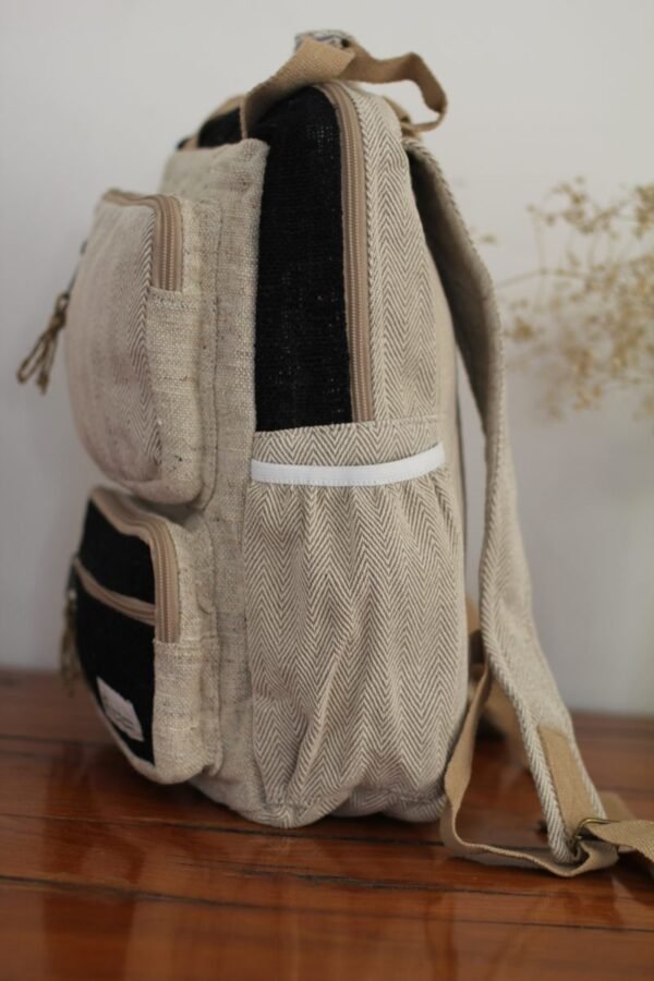 Handmade hemp maternity backpack displayed on a wooden table indoors water bottle compartment