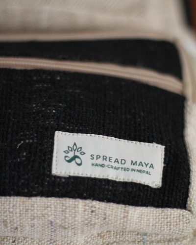 Handmade hemp maternity backpack displayed on a wooden table indoors spreadmaya logo