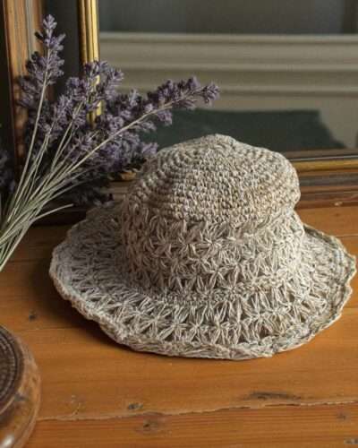Beige Nest Crochet Hat placed on a wooden table