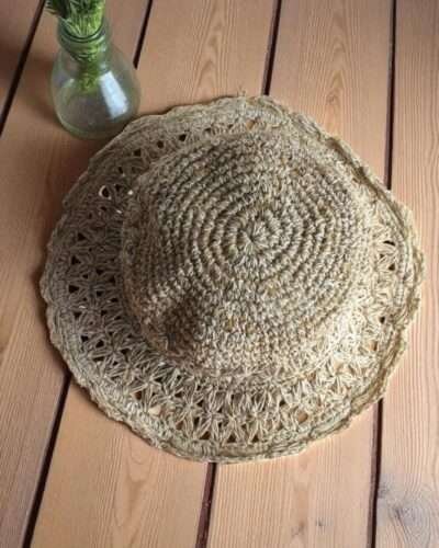 Beige Nest Crochet Hat placed on a wooden table