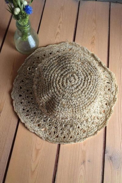 Beige Nest Crochet Hat placed on a wooden table