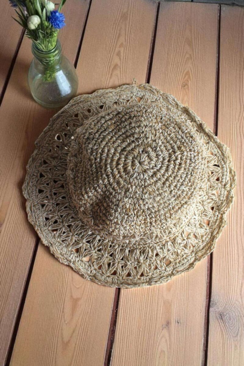Beige Nest Crochet Hat placed on a wooden table