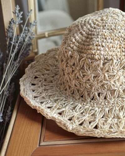 Beige Nest Crochet Hat placed on a wooden table
