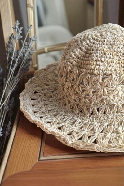 Beige Nest Crochet Hat placed on a wooden table
