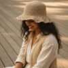 a woman wearing beige hemp crochet hat and sitting in outdoor setting