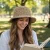 a woman wearing Kathmandu Knot crochet hat and reading a book sitting in a park