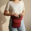 a woman carrying cotton bum bag around her waist in plain background
