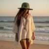 a woman wearing kumari crochet hat green and walking on the beach