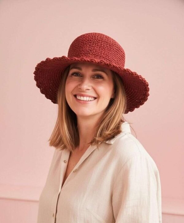 A woman wearing wide brim red crochet hat and smiling