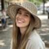 a woman wearing beige nest crochet hat and smiling in natural setting