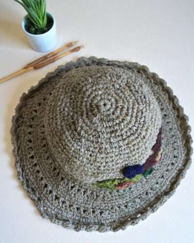 hemp crochet hat with flower embroidery placed a table