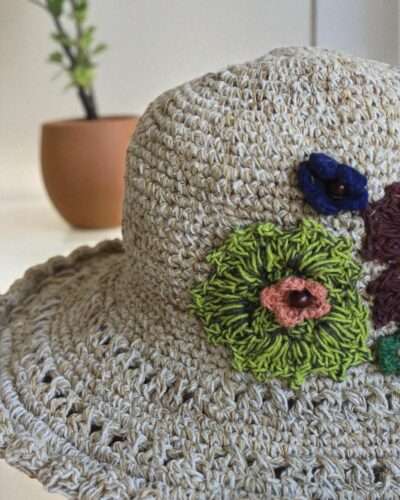 hemp crochet hat with flower embroidery placed a table
