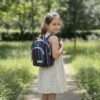 a young girl carrying hemp colorful mini backpack inoutdoor setting