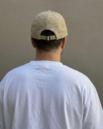 Back view of beige hemp cap worn by man, showing adjustable strap