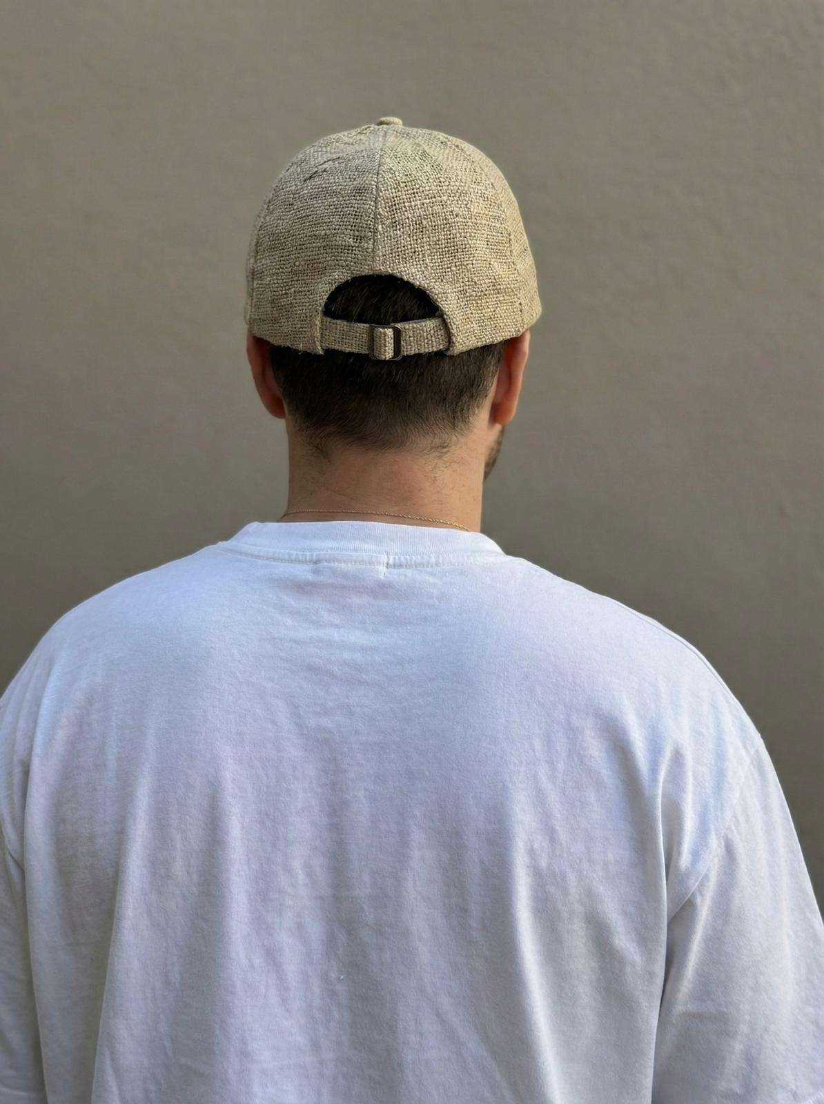 Back view of beige hemp cap worn by man, showing adjustable strap