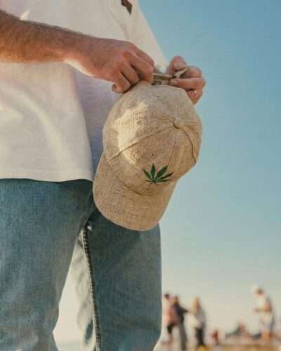 Man adjusting the strap of a beige hemp cap, handmade and breathable