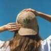 Woman posing from back wearing beige hemp cap showing leaf embroidery