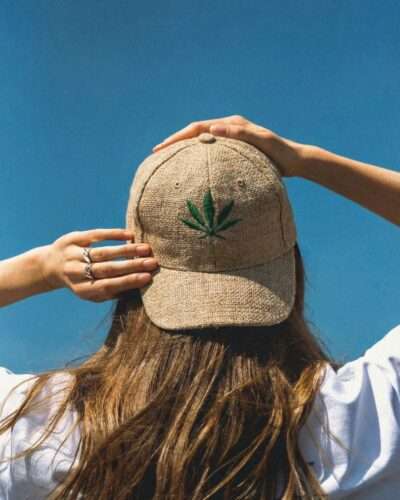Woman posing from back wearing beige hemp cap showing leaf embroidery