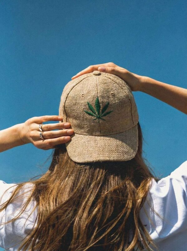 Woman posing from back wearing beige hemp cap showing leaf embroidery