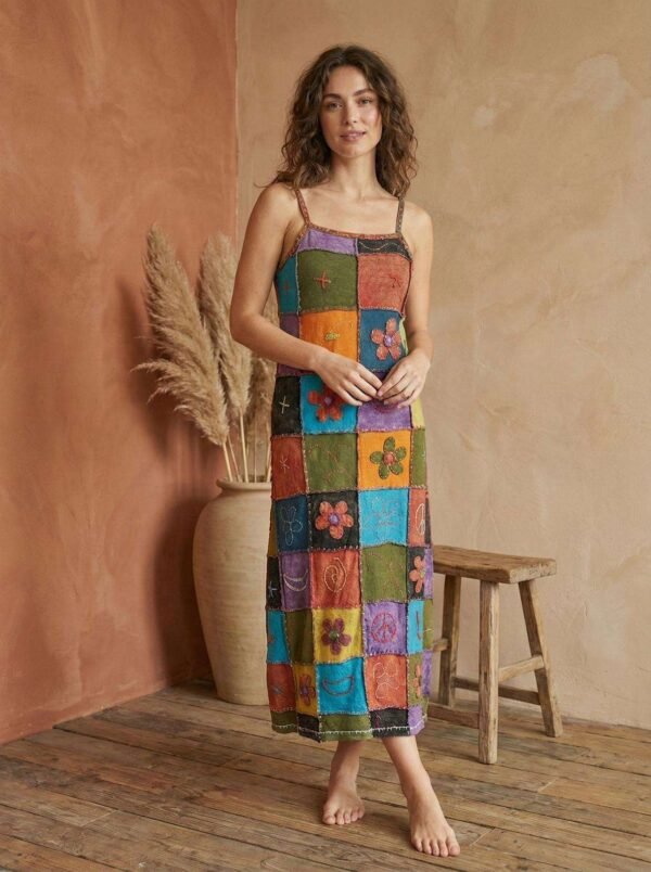 a model wearing retro patchwork dress and posing in earthy background