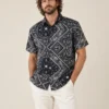 Men’s black mandala hemp short sleeve shirt by Spreadmaya worn by male model, relaxed front pose on beige background.
