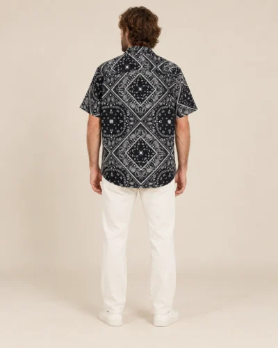 Back view of men’s black mandala hemp short sleeve shirt by Spreadmaya worn by male model on beige background.