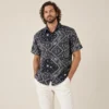 Men’s black mandala hemp short sleeve shirt by Spreadmaya worn by male model, relaxed front pose on beige background.