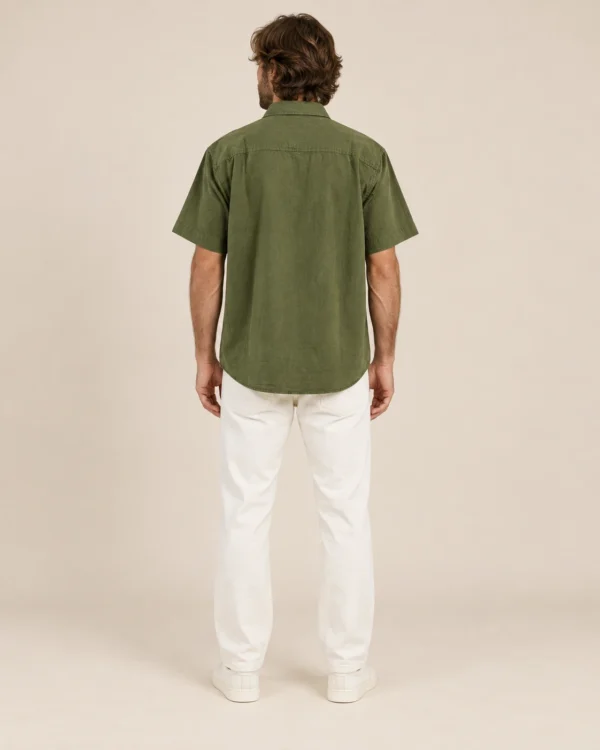 Back view of men’s olive green hemp short sleeve shirt by Spreadmaya worn by male model on beige background.