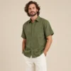 Relaxed view of men’s green short sleeve hemp shirt by Spreadmaya worn by male model on beige background.