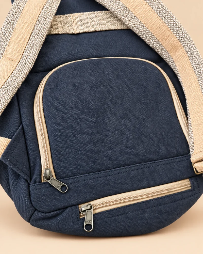 Close-up of rear zippered storage compartment on charcoal blue SpreadMaya hemp maternity backpack.