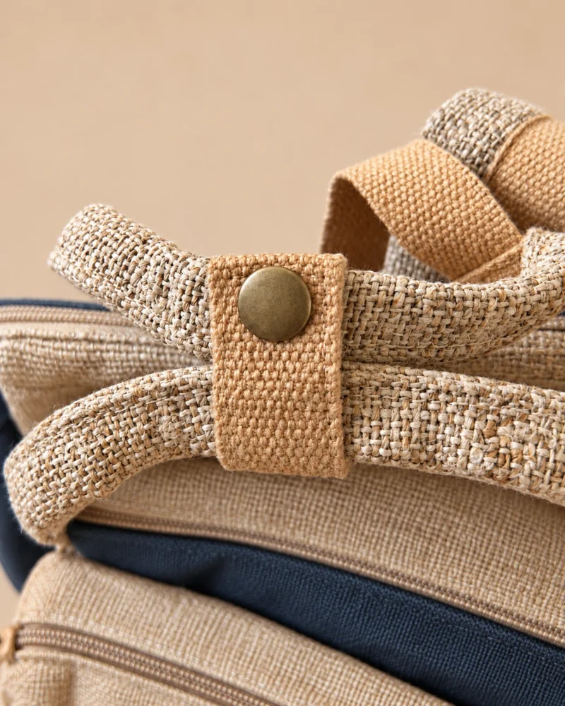 Close-up of natural hemp carry handles secured with a buttoned strap on SpreadMaya maternity backpack.