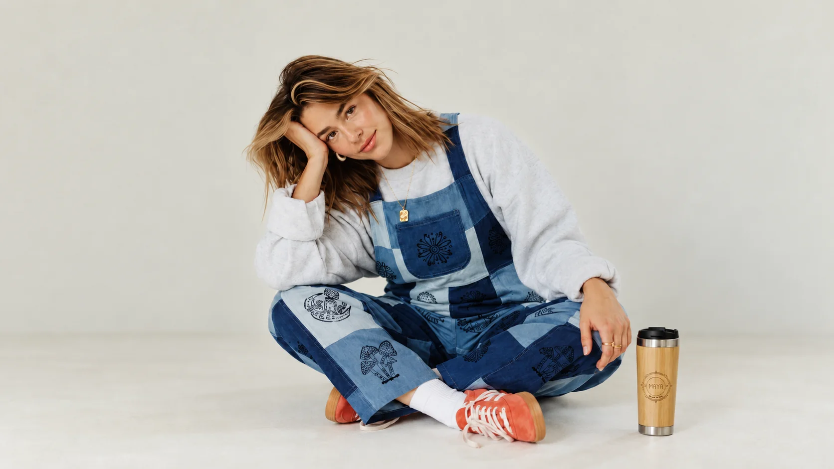 A model wearing a Spread Maya Moon Patch overall and a Maya bamboo mug. Ethically handmade in Nepal
